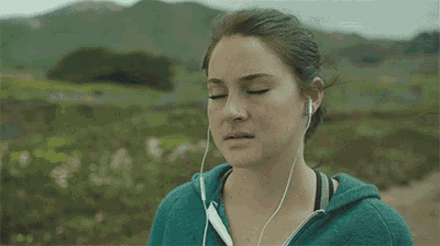 a woman wearing ear buds looks down at something