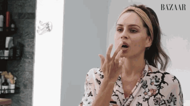 a woman is applying lipstick to her lips in front of a mirror in a bathroom .
