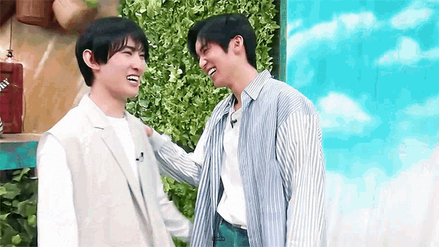 a couple of men are standing next to each other and laughing .