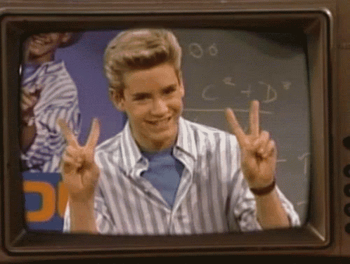 a young man giving a peace sign in front of a chalkboard