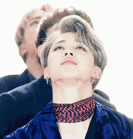 a man wearing a blue jacket and a leopard print scarf looks up at the sky .