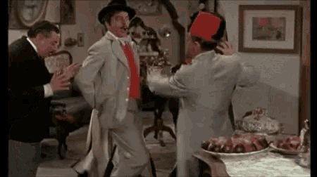a group of men are standing in a room and one of them is wearing a fez