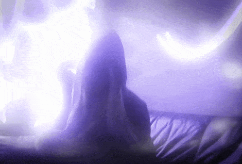 a woman is laying on a couch in a dark room with purple lights behind her