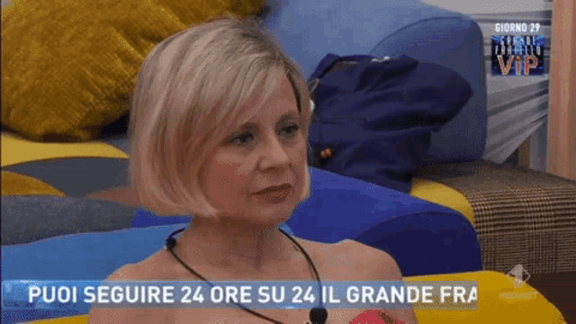 a woman is sitting on a couch with the words puoi seguire 24 ore su 24 il grande fra on the screen