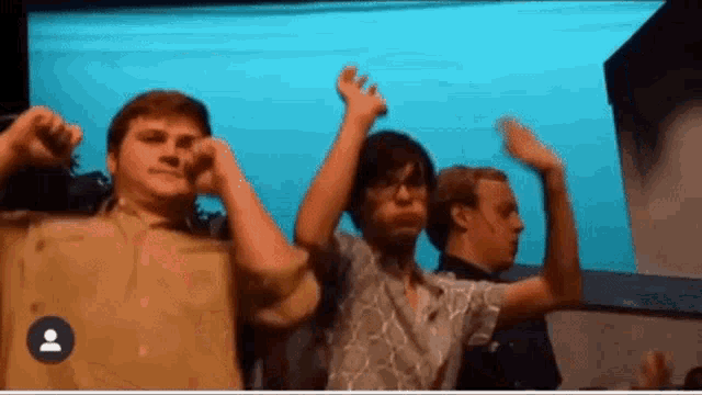 a group of young men are dancing on a stage with their hands in the air .