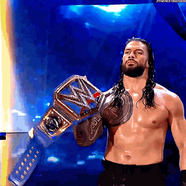 a shirtless wrestler is holding a wrestling championship belt