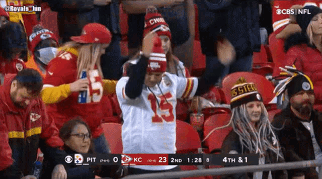 a fan wearing a hat that says ' chiefs ' on it stands in the stands