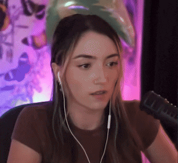 a woman wearing headphones is sitting in front of a microphone and looking at the camera .
