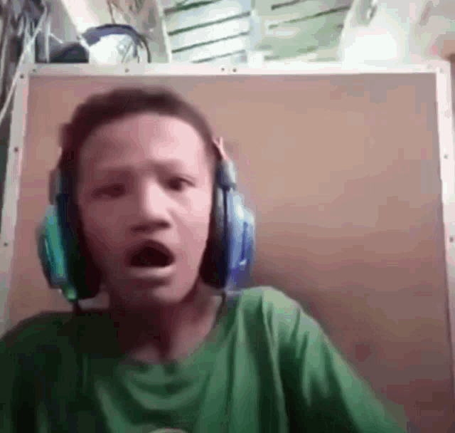 a young boy wearing headphones is making a surprised face .