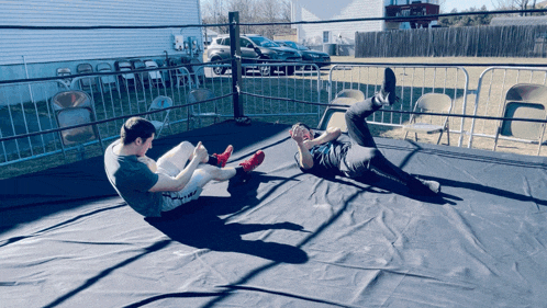 two men wrestling in a ring with a fence around them