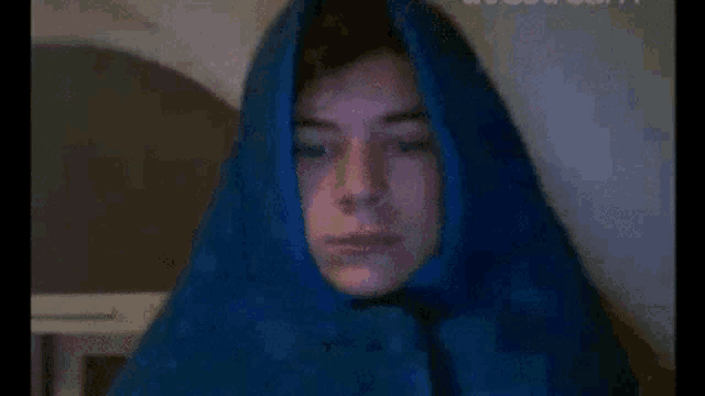 a man wearing a blue scarf around his head is looking at the camera .