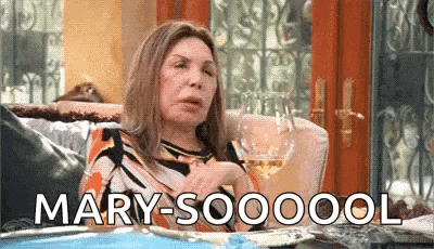 a woman is sitting on a couch holding a glass of wine and saying mary-soooool .