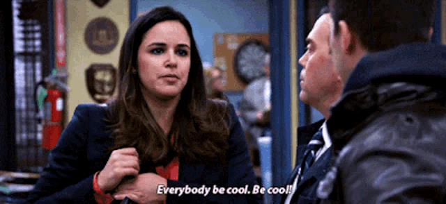 a woman says " everybody be cool be cool " in front of two men