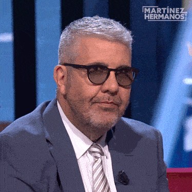 a man wearing glasses and a suit is on a martinez hermanos show