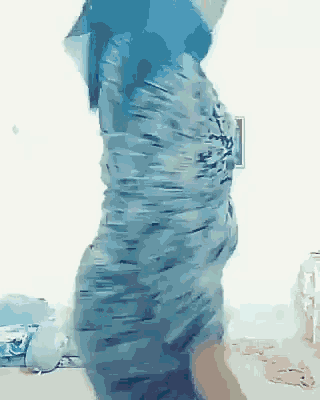 a woman in a blue dress is dancing in a bedroom