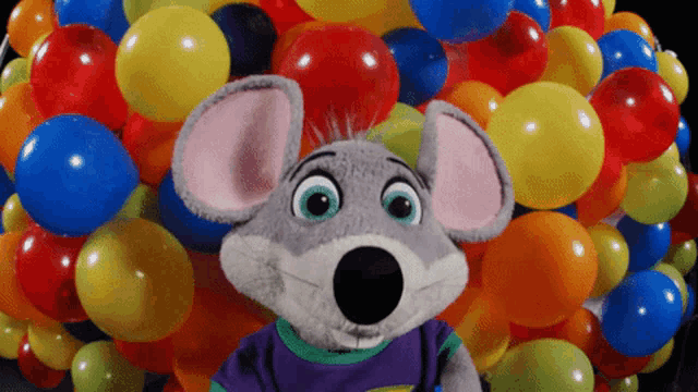 chuck e cheese mouse surrounded by colorful balloons on a black background