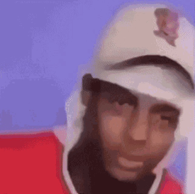 a man wearing a white hat and a red shirt is making a funny face .
