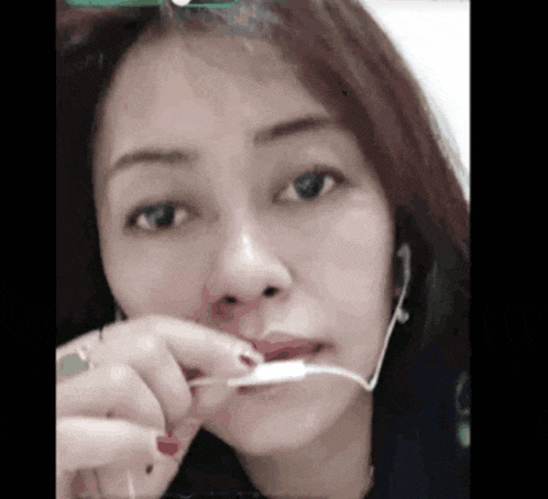 a woman is holding a toothbrush in her mouth .
