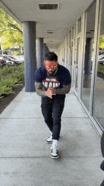 a man wearing a t-shirt that says main is standing on a sidewalk