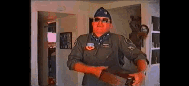a man in a military uniform is standing in a living room holding a bottle .