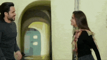 a man and a woman are standing next to each other and smiling at each other .