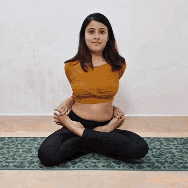 a woman in a yellow top is sitting on a green mat