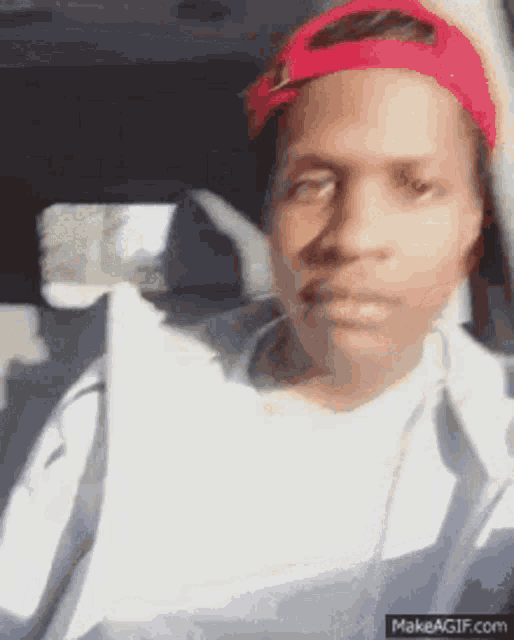 a man wearing a red hat and a white shirt is sitting in the back seat of a car .