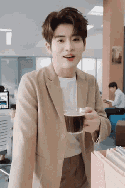 a man in a tan jacket is holding a cup of coffee