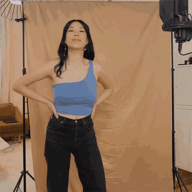 a woman in a blue top and black jeans kicks her leg
