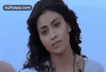 a close up of a woman 's face with a serious look on her face and a blue sky in the background .