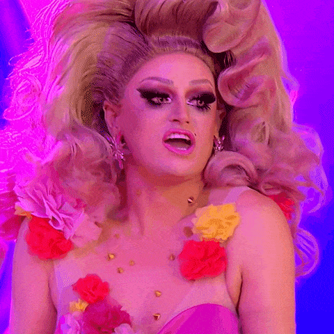 a drag queen wearing a pink dress with flowers on her chest