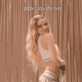 a woman in a crop top is dancing in front of a curtain with the words pov sos de vic written on it .