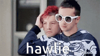 two men are standing next to each other and one of them has red hair and the other has white sunglasses on .
