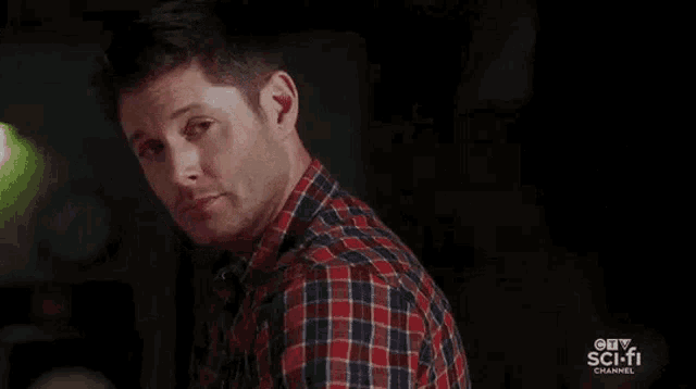a man in a plaid shirt is making a funny face and says boom .