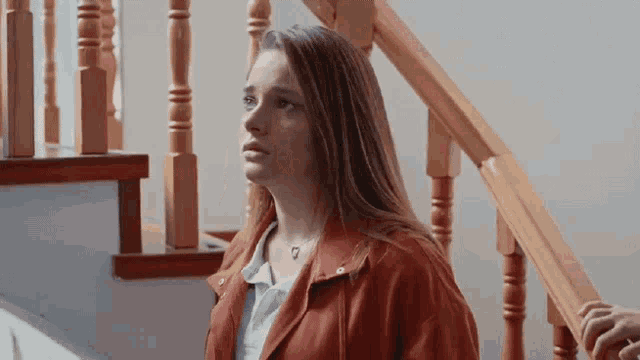 a young woman in a red jacket is standing on a set of stairs .