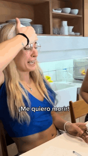 a woman sitting at a table with the words me quiero morir written below her