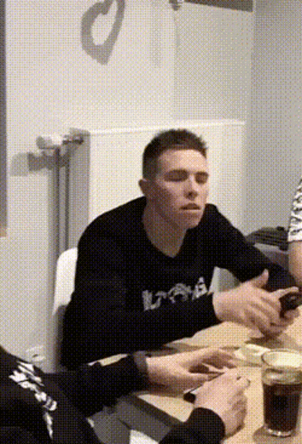 a man sitting at a table with a sweatshirt that says ' uaa ' on it