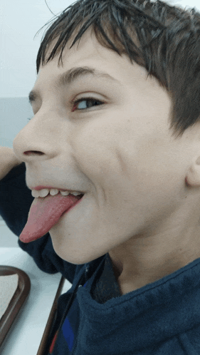 a young boy sticking his tongue out while making a funny face