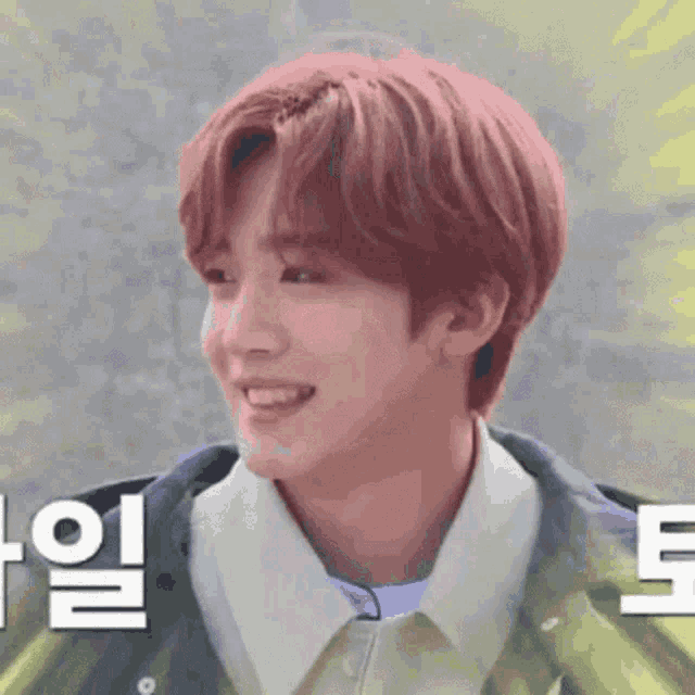 a young man with red hair is smiling and wearing a green jacket