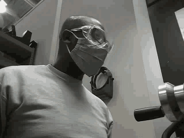a man wearing a mask and goggles is standing in a room with a machine .