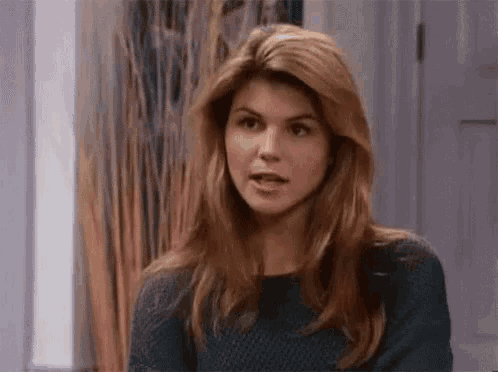 a woman in a sweater is making a funny face .