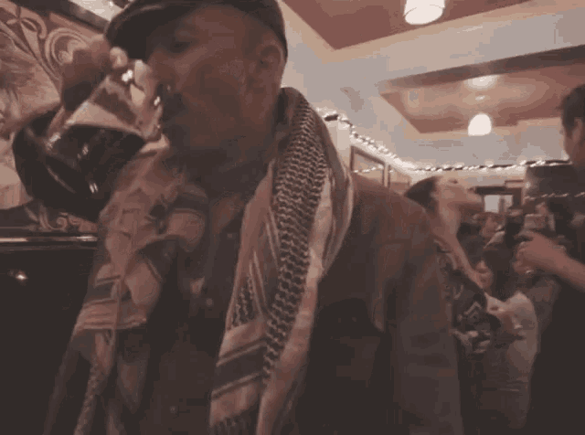 a man with a scarf around his neck is standing in a crowd of people