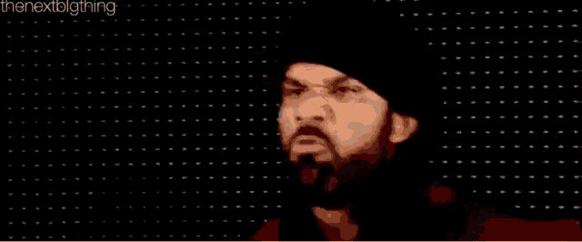 a man with a beard and hat is making a funny face .