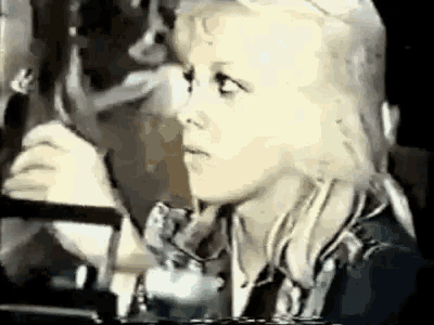 a woman with blonde hair is sitting in a car talking on a phone .