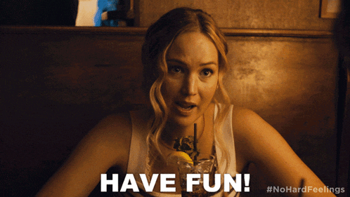 a woman sitting at a table with a drink and the words have fun behind her