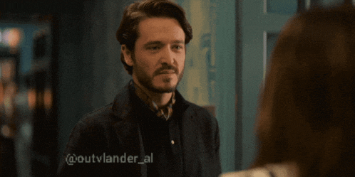 a man with a beard is looking at a woman with the hashtag @outvlander_al on the bottom