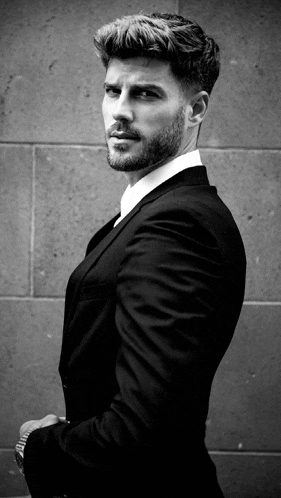 a man with a beard is wearing a suit and white shirt