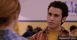 a man in a striped shirt and a yellow shirt is talking to a woman in a gym .