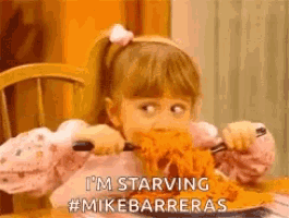 a little girl is sitting at a table eating spaghetti with a knife and fork .