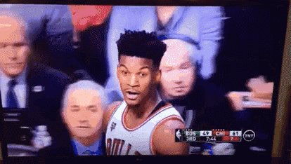 a basketball player is standing in front of a crowd during a game on a television .